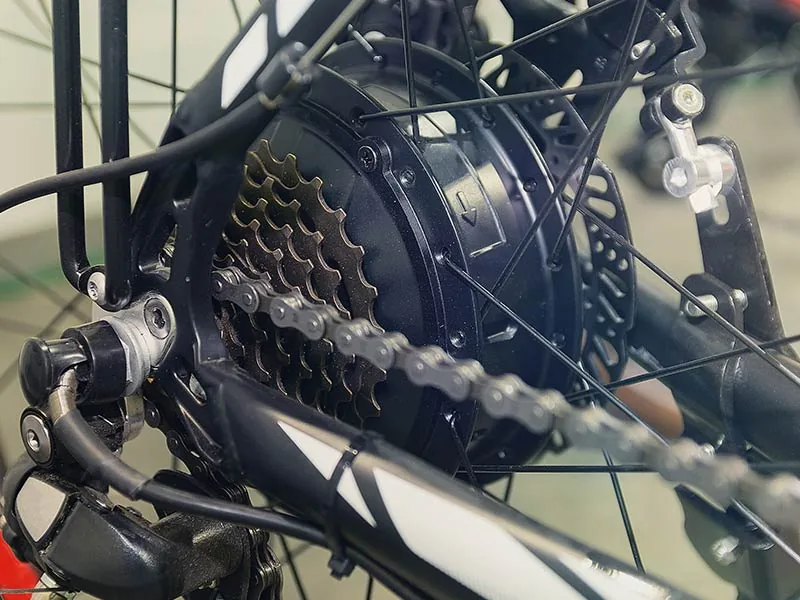 Close-up of a bicycle gear system and chain in a workshop setting. Details of cogs, black and silver metal parts, evoke precision and functionality.