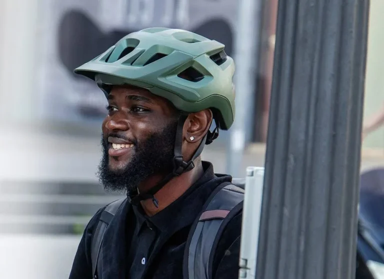 A smiling rider in a green helmet on a city street